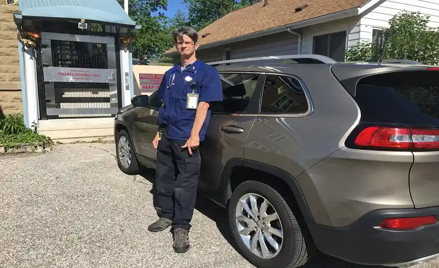 Garrick Pattenden standing in front of his car in a professional attire